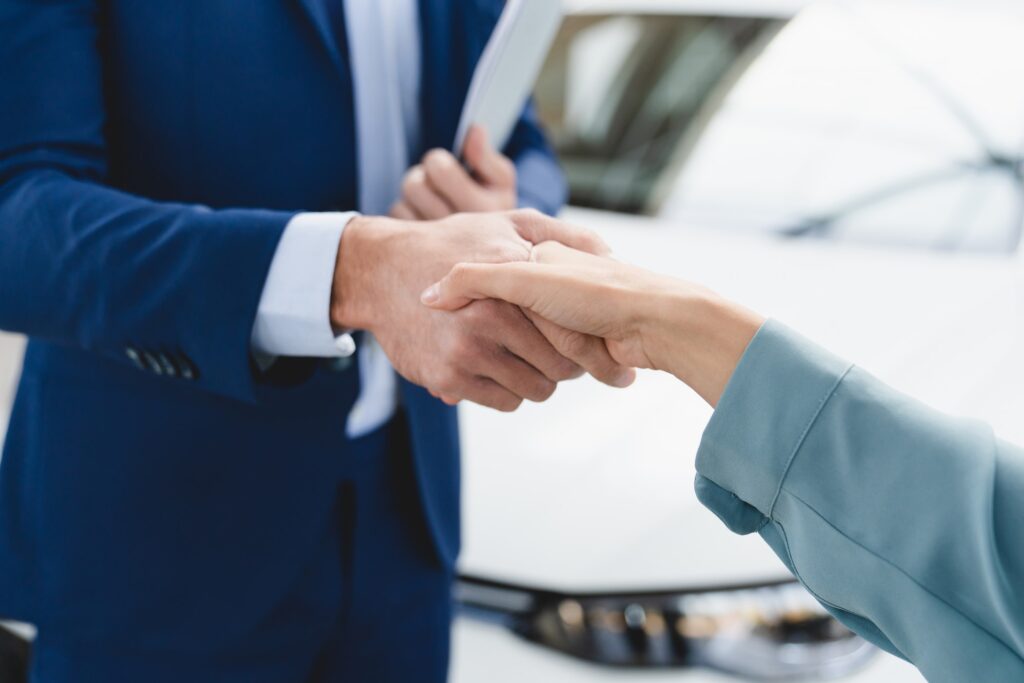 Shop assistant handshake with female customer client after buying purchasing new car. Good deal.