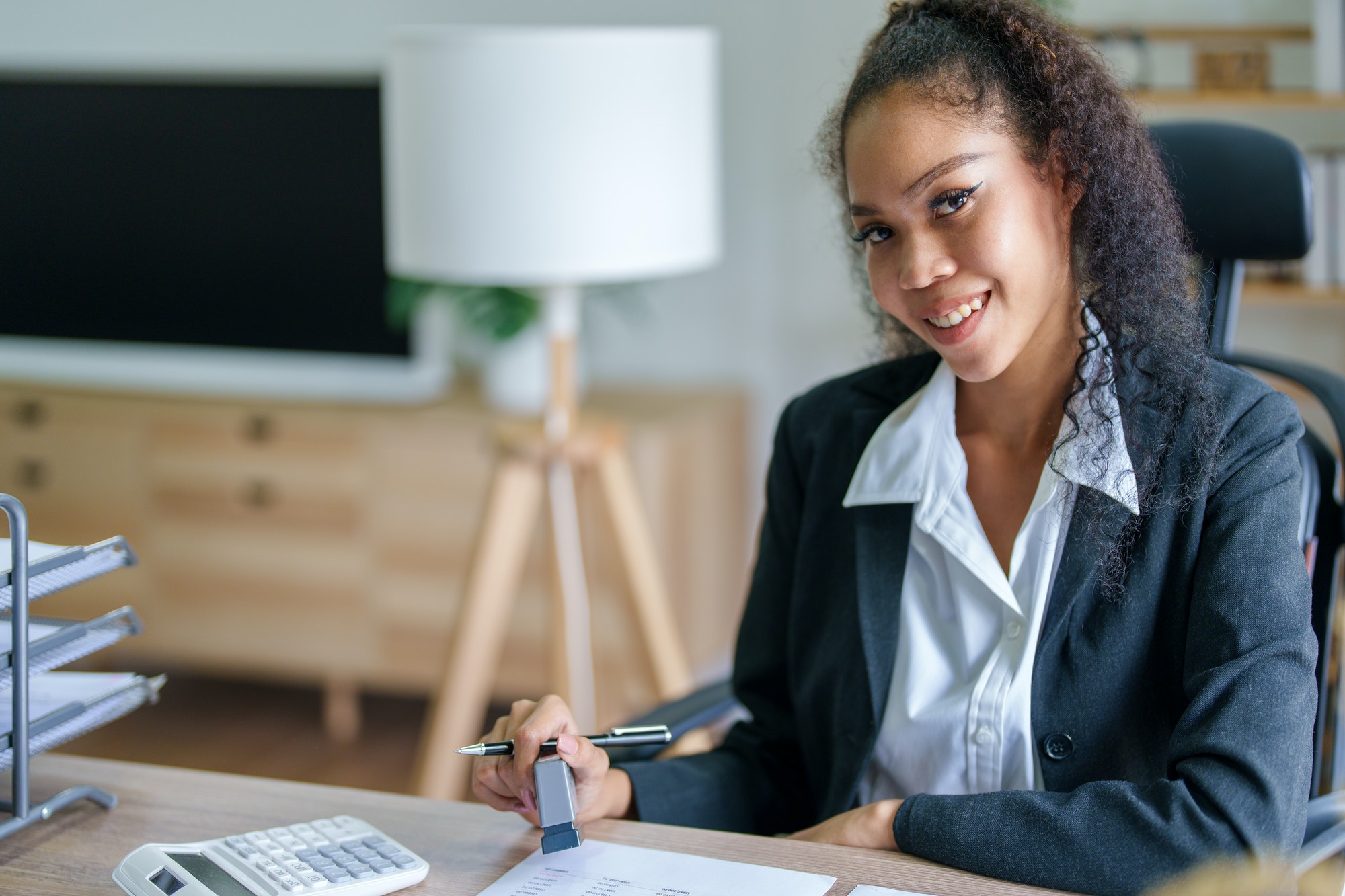 African Americans businesswoman stamping budget approval on financial documents